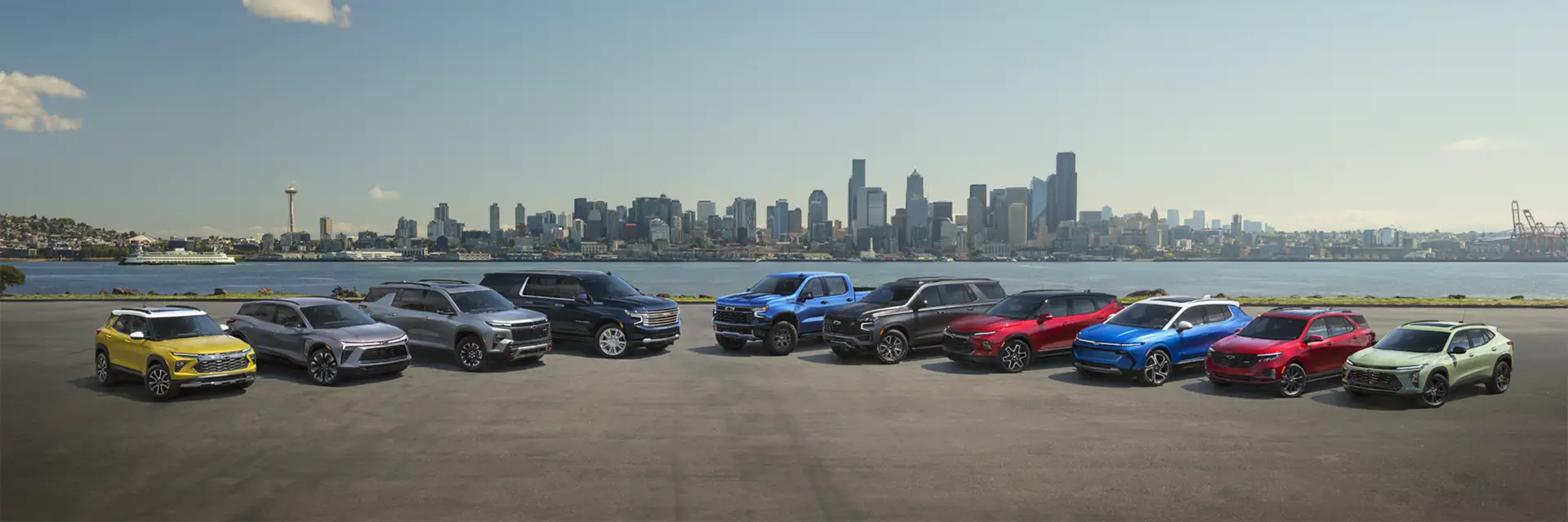 ten Chevrolet vehicles lined up outside of the city near the river