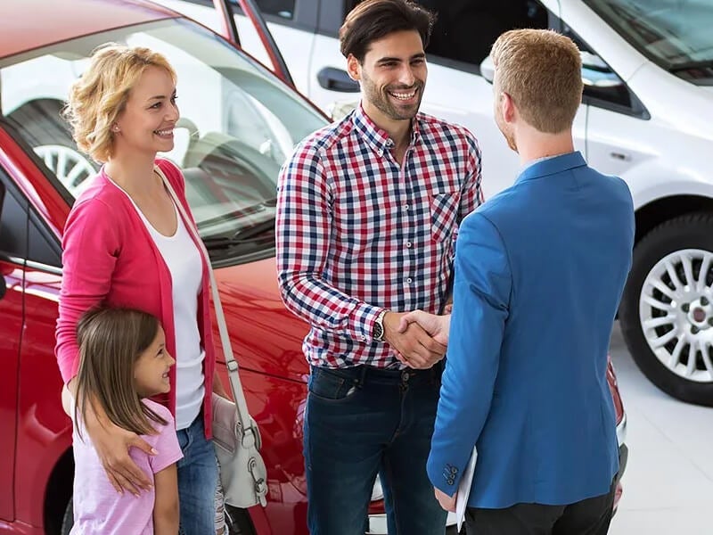 service manager shaking hands with the family after they purchased a vehicle