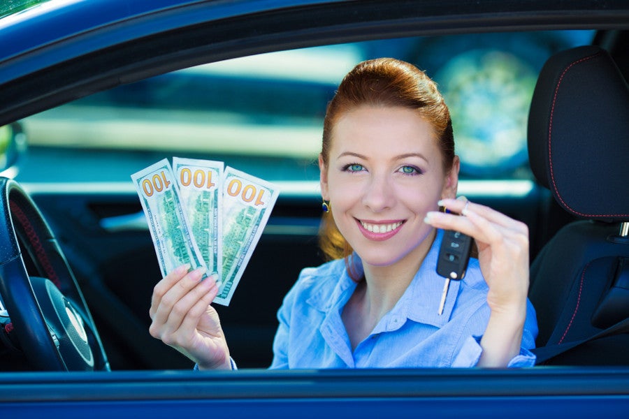 Woman in her car holding up money and her car keys