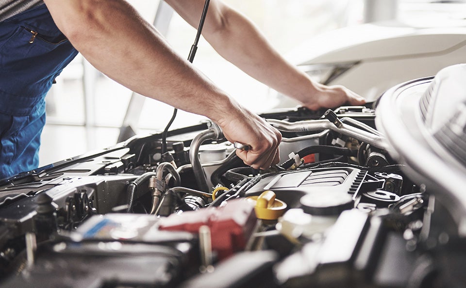 Technician working on the engine inside of their dealership shop